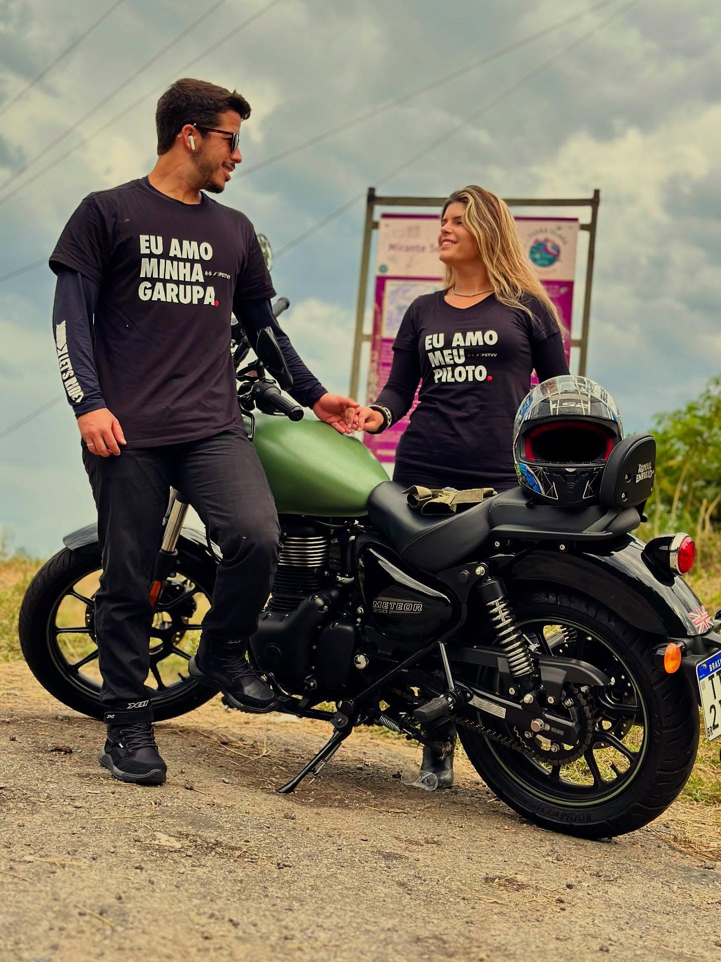 Casal motociclista usando camisetas Pistaviva ao lado de uma moto