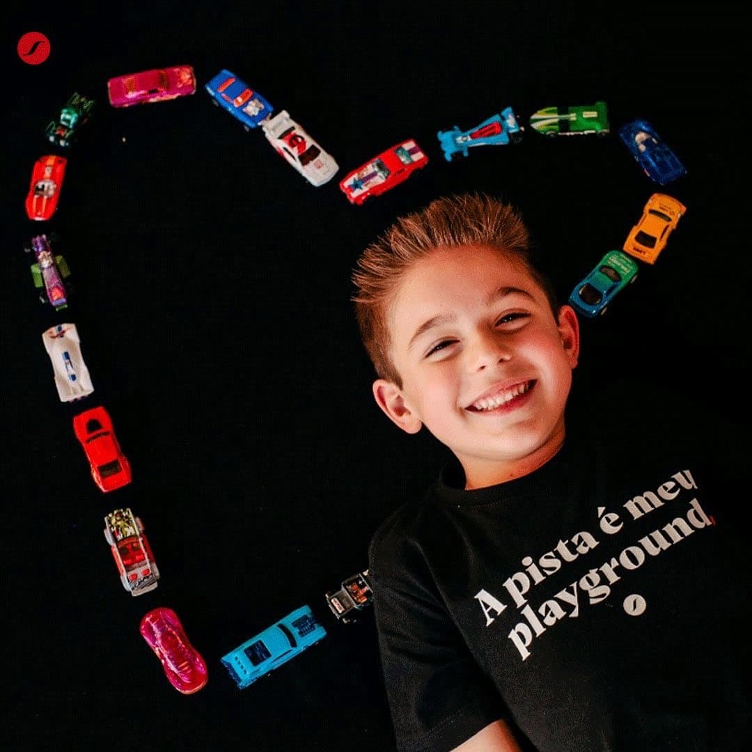 Criança usando camiseta Pistaviva entre miniaturas de carros