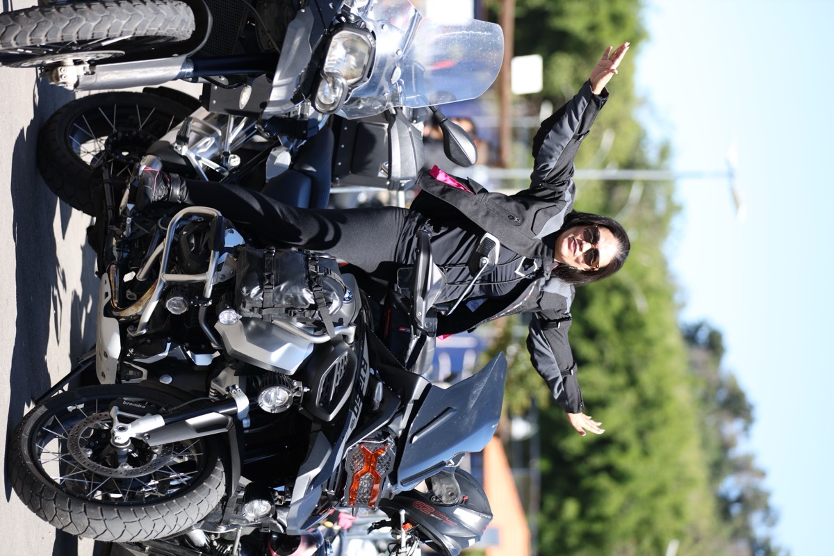 Motociclista de braços abertos no pátio de motos