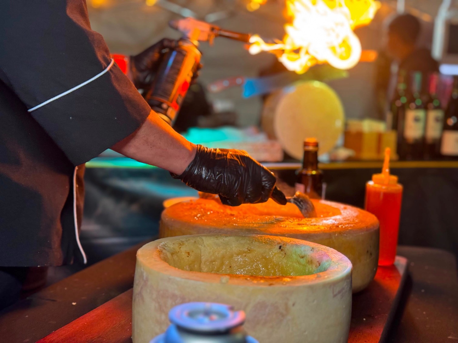 Chef maçaricando roda de queijo em festival gastronômico no parque