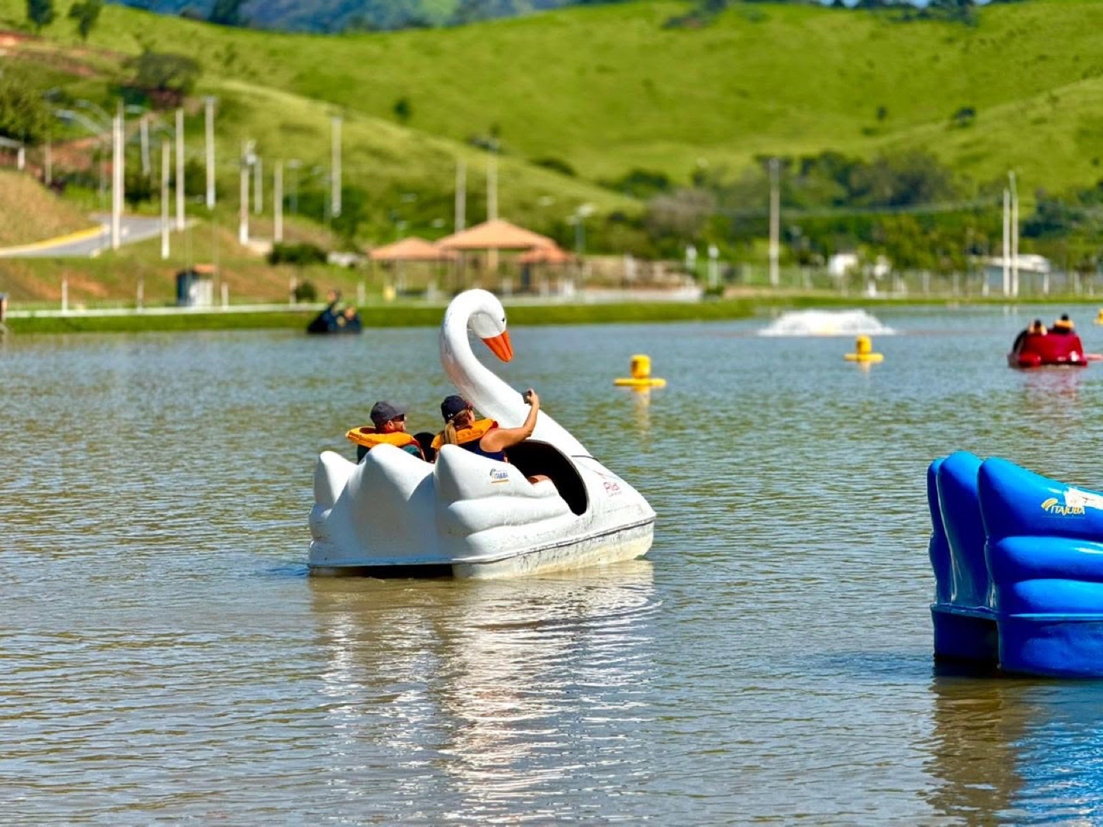 Pedalinho em formato de cisne no lago do Parque da Cidade de Itajubá, com a serra verde ao fundo