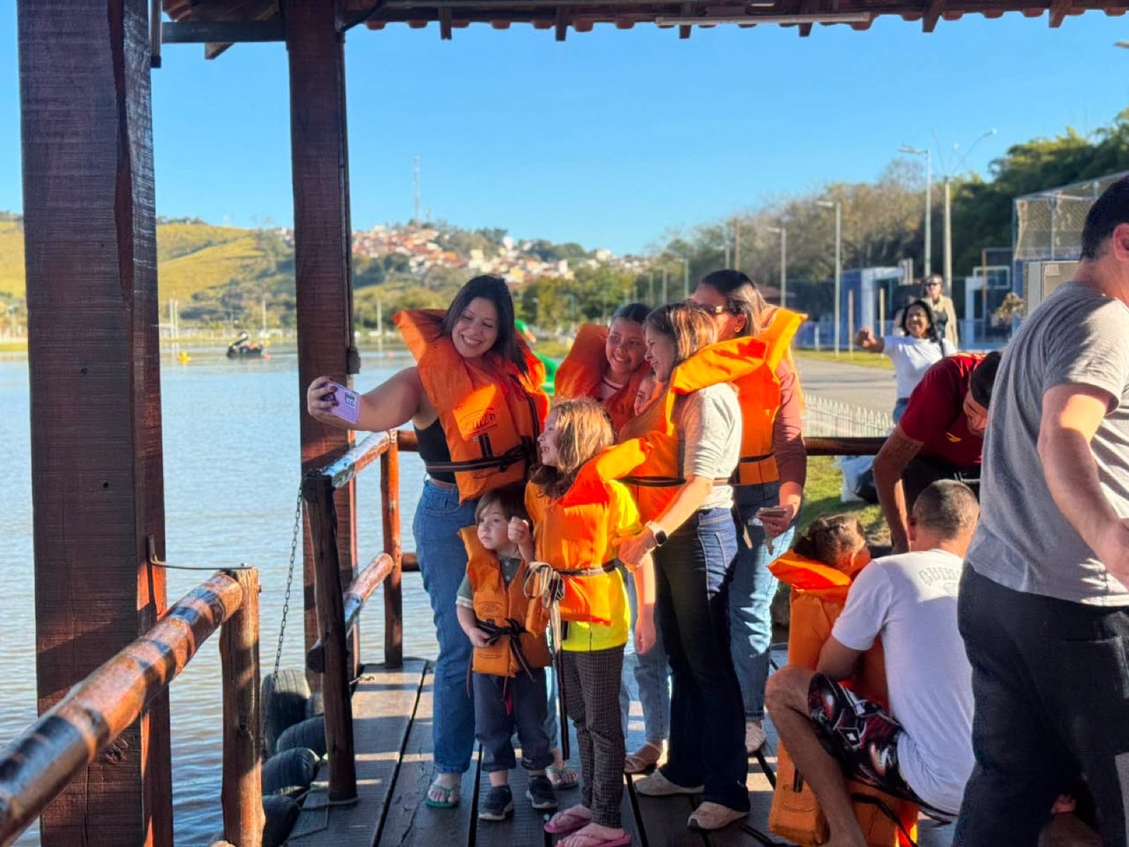 Família de colete salva-vidas tirando selfie no píer do pedalinho